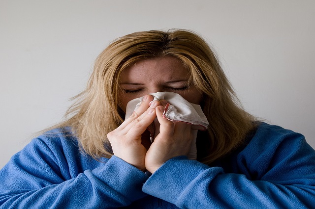 woman sneezing into tissue